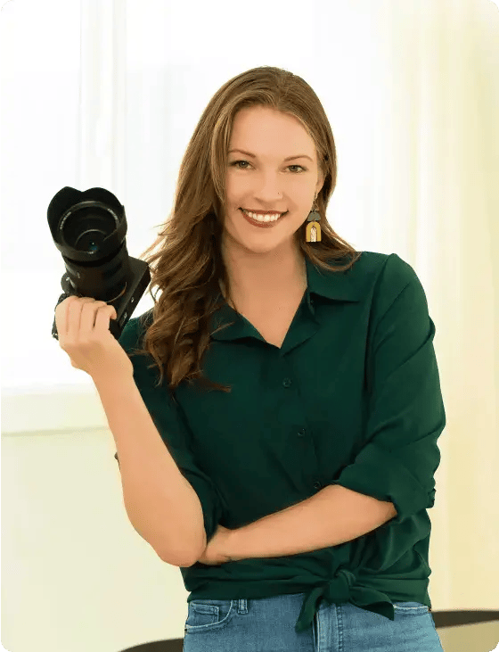 photographer Ashley Blackmer posing with a mirrorless camera for shooting real estate photography